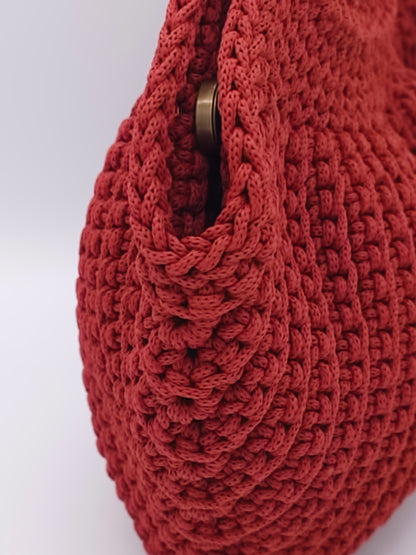 Close-up of a burnt orange bag with antique gold clasp on a white background
